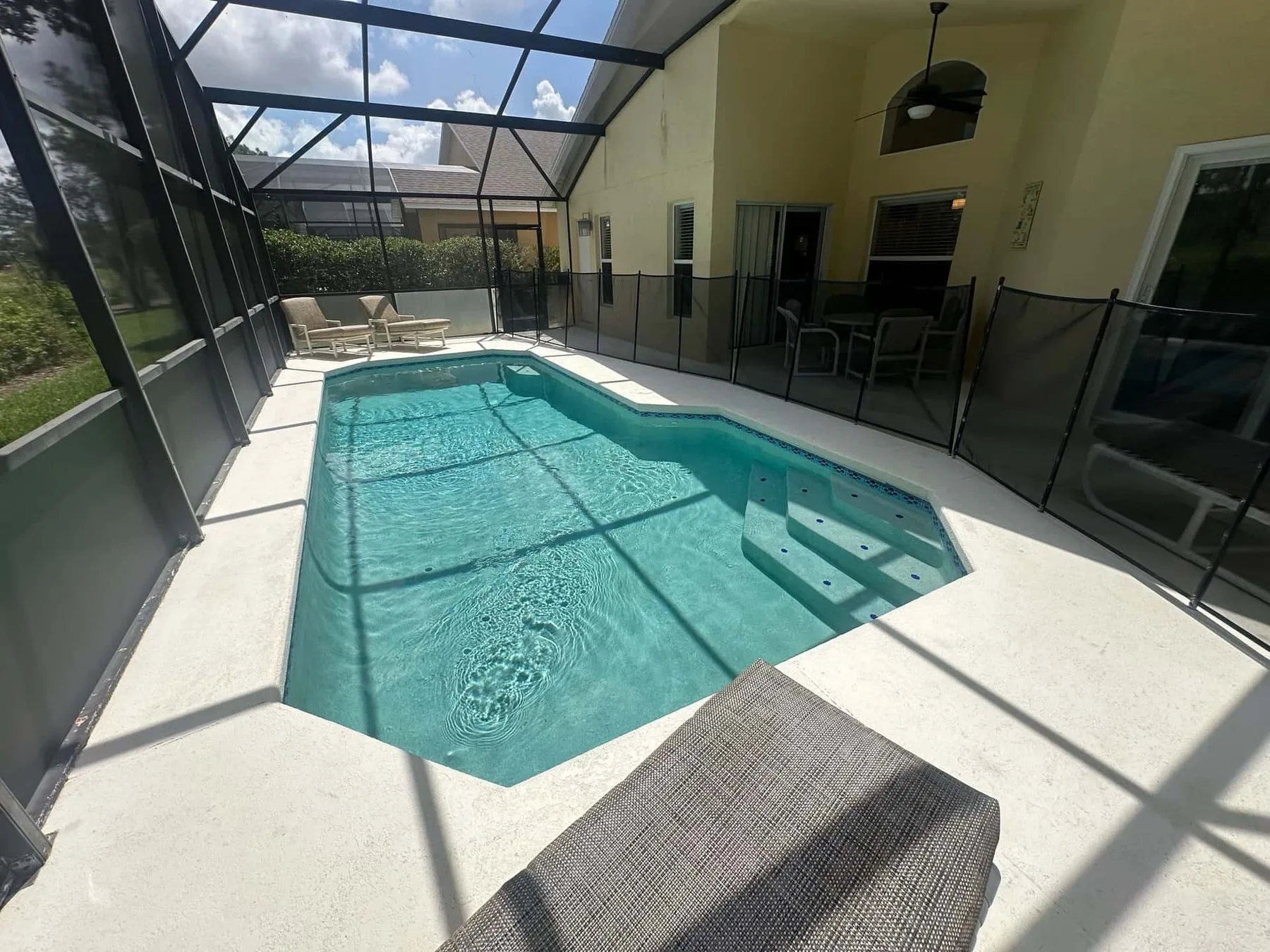 Una piscina interior con mosquitero, una zona de escalones poco profundos y asientos cerca.