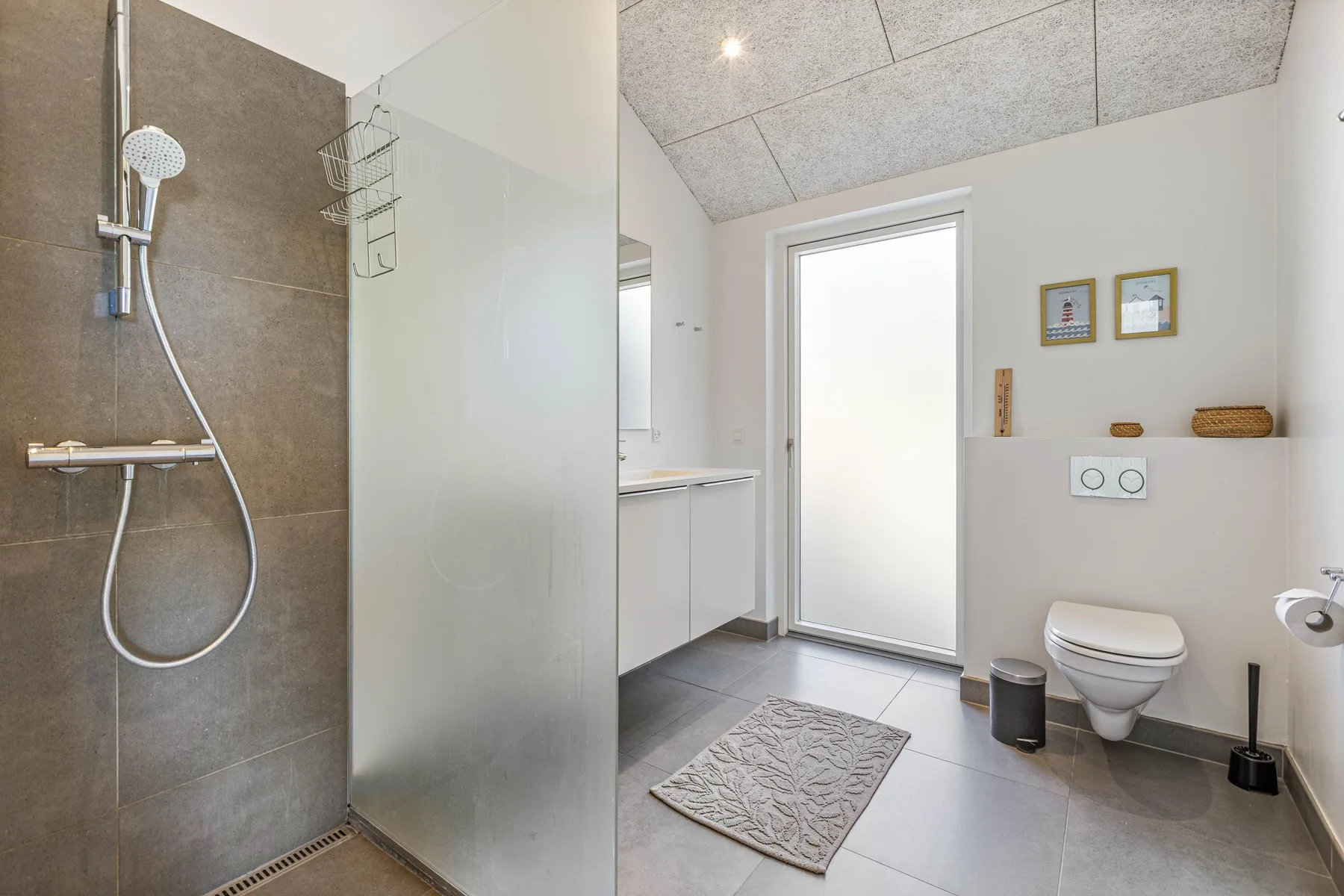 Un baño luminoso con ducha, lavabo e inodoro.
