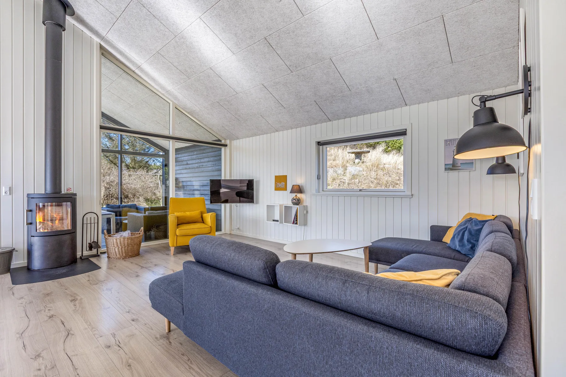 Una sala de estar luminosa con asientos, grandes ventanas y una estufa de leña.