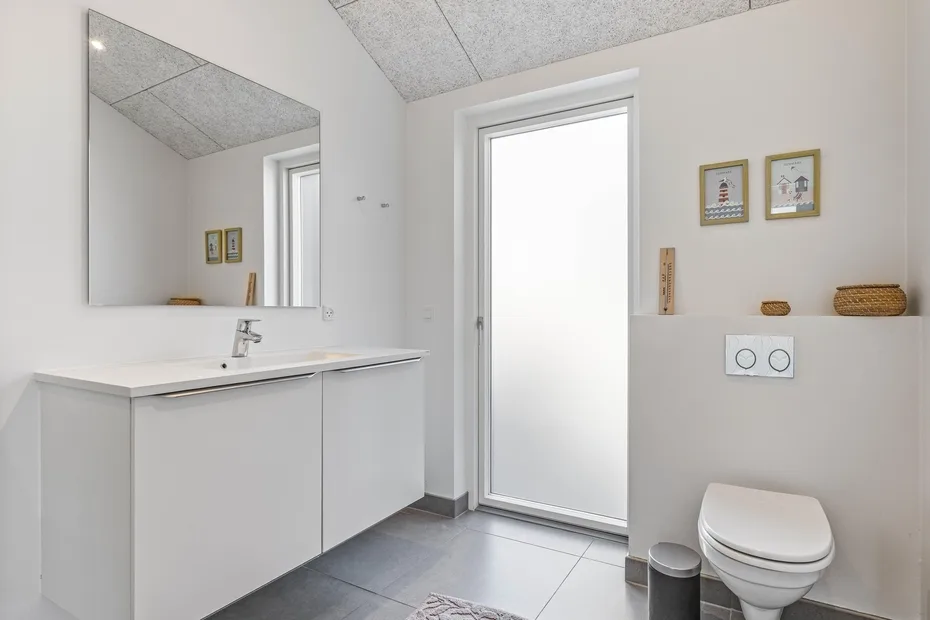 Un baño luminoso con lavabo, espejo e inodoro.