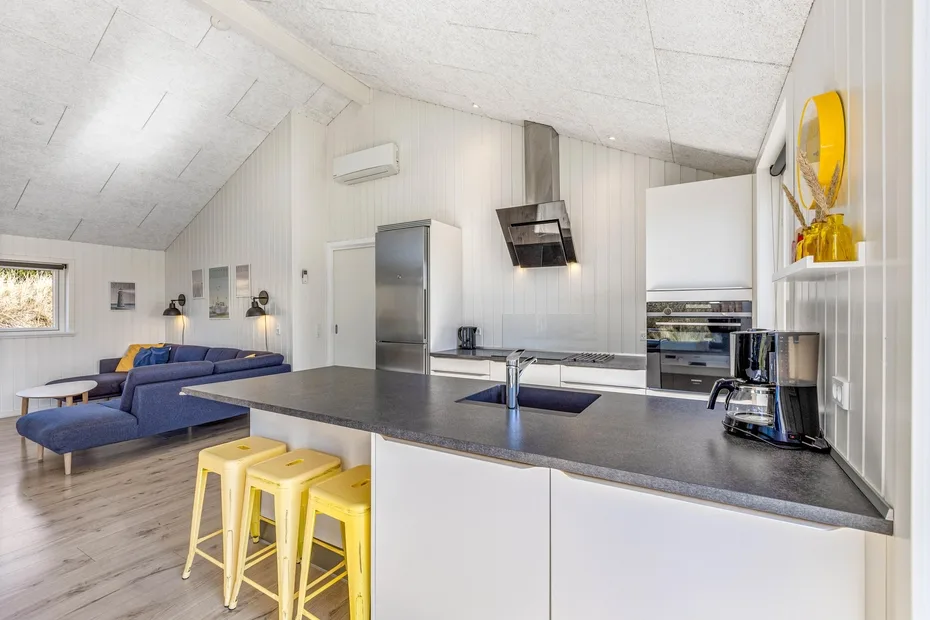 Cocina y sala de estar de concepto abierto con una isla oscura y asientos azules.