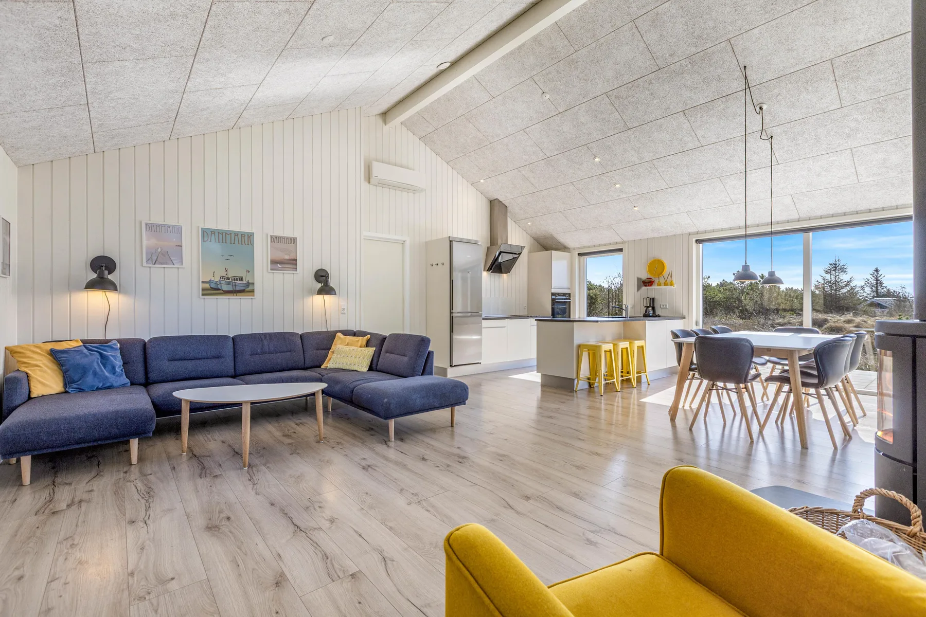 Una luminosa sala de estar y comedor de concepto abierto con cocina y grandes ventanas.