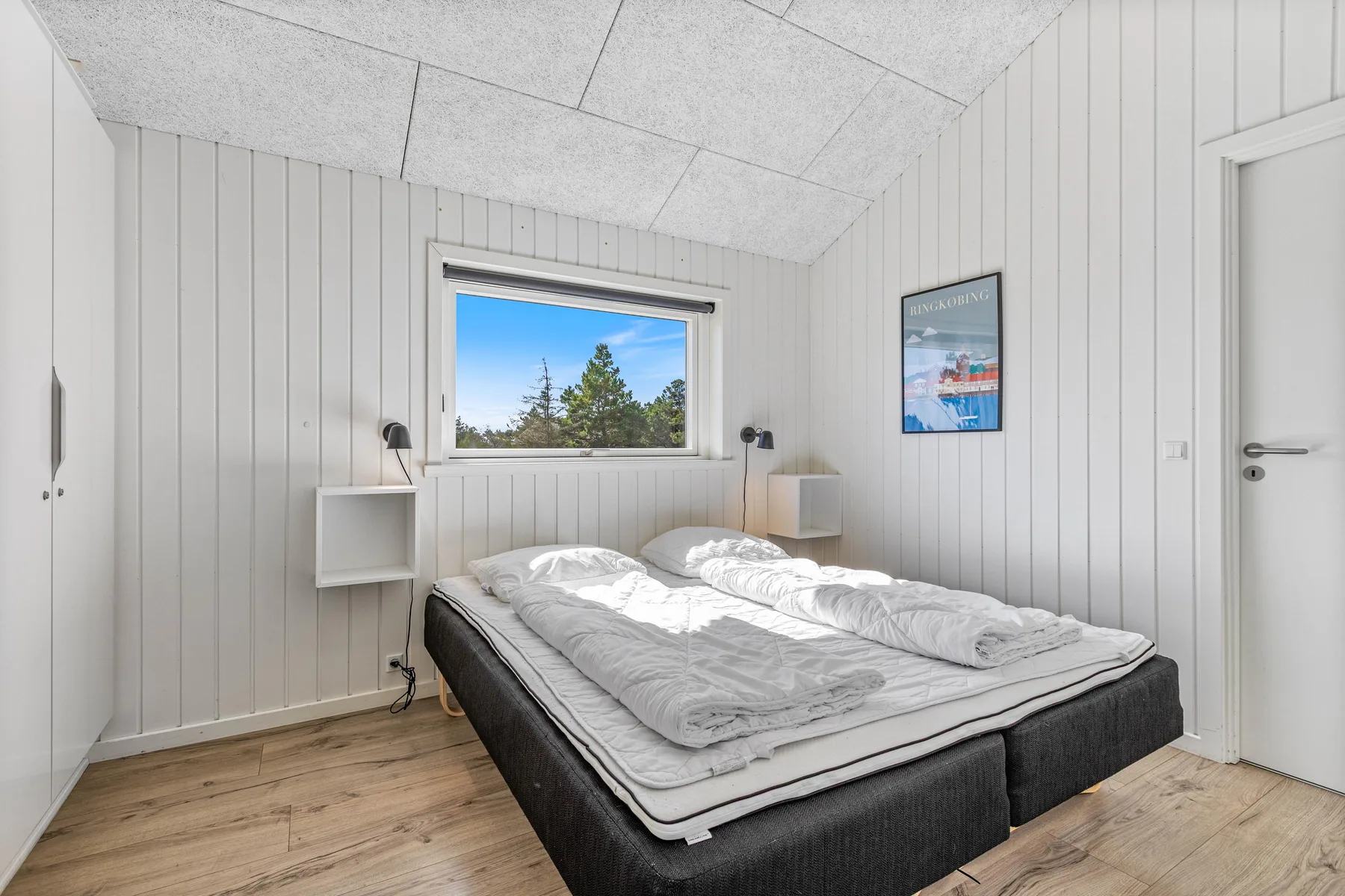 Un dormitorio luminoso con una cama grande bajo una ventana.