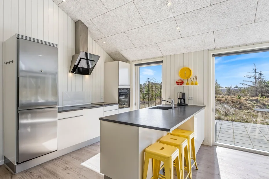 Una cocina moderna y luminosa con una isla central y grandes ventanas con vistas al paisaje.