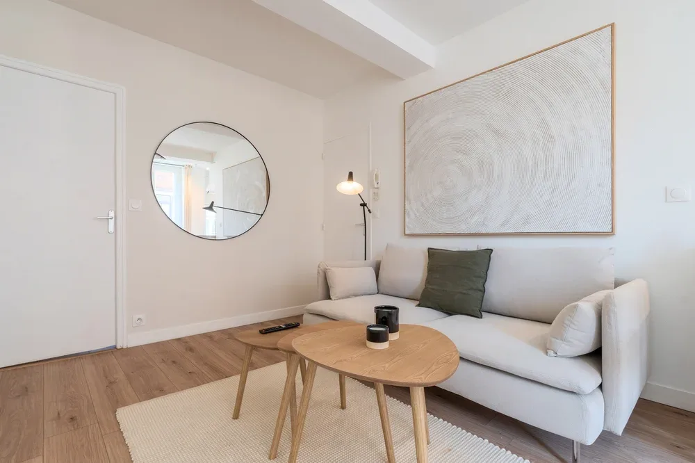 A bright living room with a light-colored sofa and round wooden coffee table.