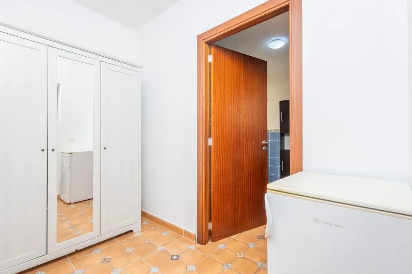 Dormitorio con un armario blanco junto a una puerta de madera abierta.