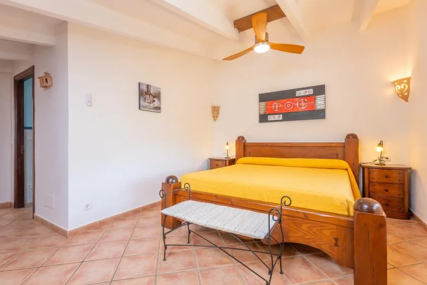Un dormitorio con una cama de madera vestida con ropa de cama amarilla.