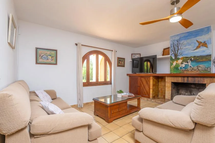 Una sala de estar con asientos beige, una mesa de centro de madera y una chimenea.