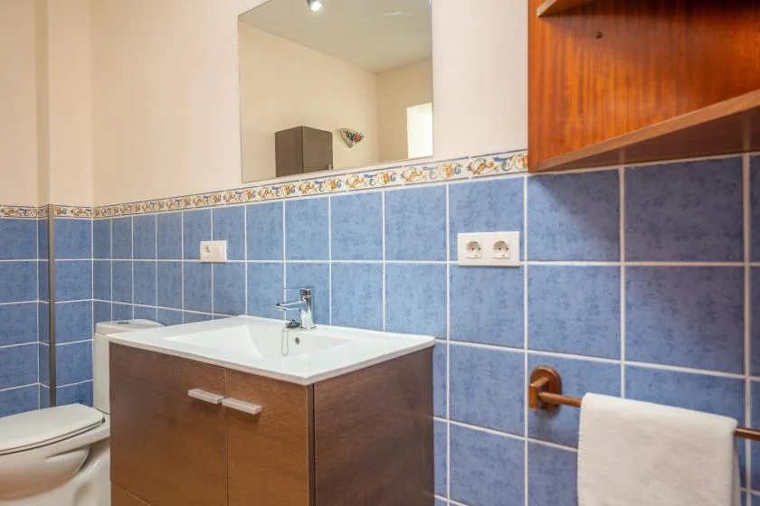 Un baño con lavabo, inodoro y paredes de azulejos azules.