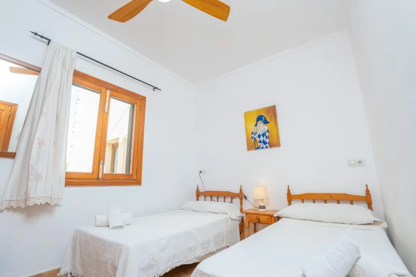 Un dormitorio luminoso con dos camas bajo un ventilador de techo.