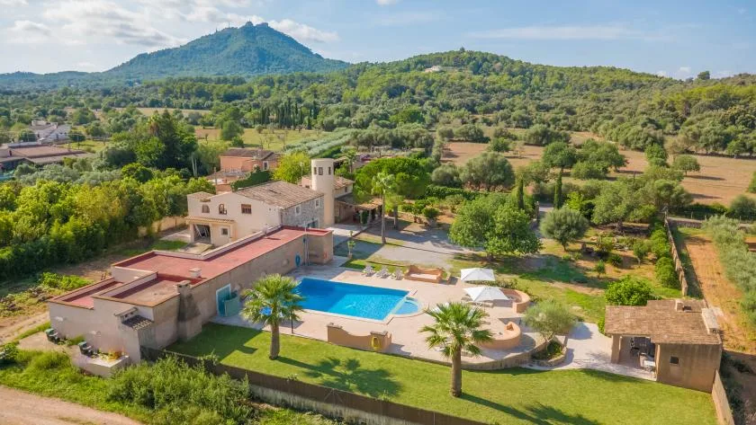 Vista aérea de una propiedad rural con piscina y colinas verdes.
