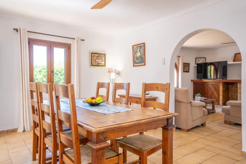 Comedor con una mesa de madera y sillas junto a una ventana luminosa.