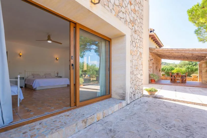 Un dormitorio da a un patio de piedra junto a una zona de comedor al aire libre.