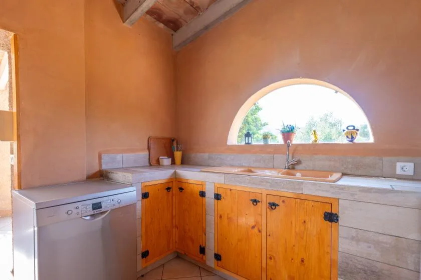 Una cocina de tonos cálidos con gabinetes de madera, lavavajillas y una ventana arqueada.