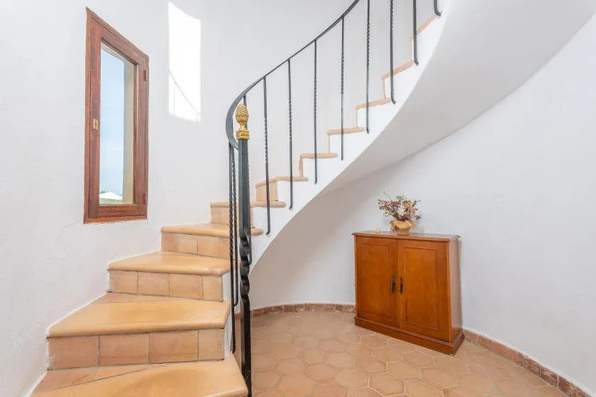Una escalera de baldosas se curva hacia arriba junto a un armario de madera.