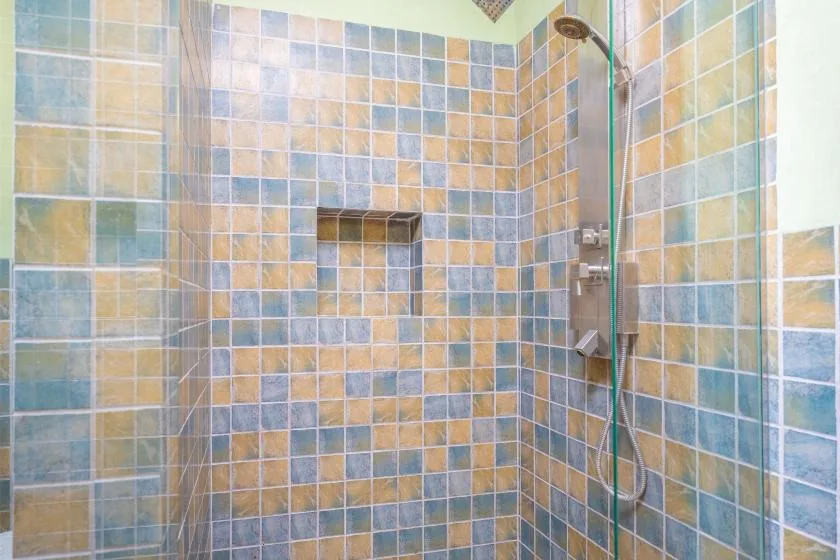 Una ducha con azulejos, un nicho empotrado y un cabezal de mano.