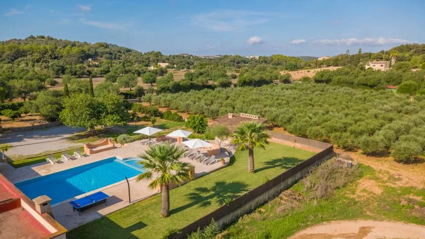 Una piscina y jardines ajardinados ofrecen vistas a un campo verde y ondulado.
