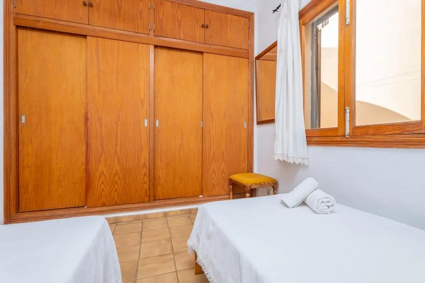 Un dormitorio con dos camas, armarios de madera y una ventana.