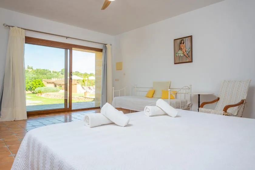 Un dormitorio luminoso con ropa de cama blanca y puertas corredizas de vidrio que dan a un patio.