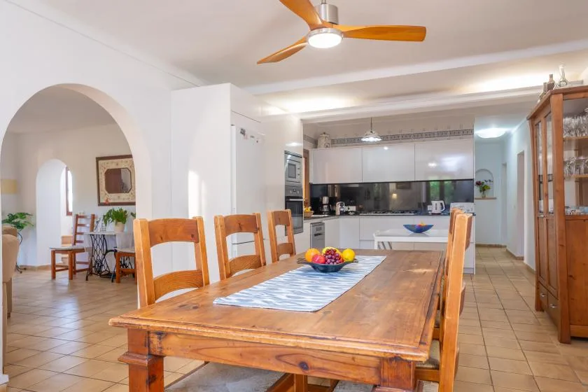 Un comedor con una mesa de madera y una cocina abierta al fondo.