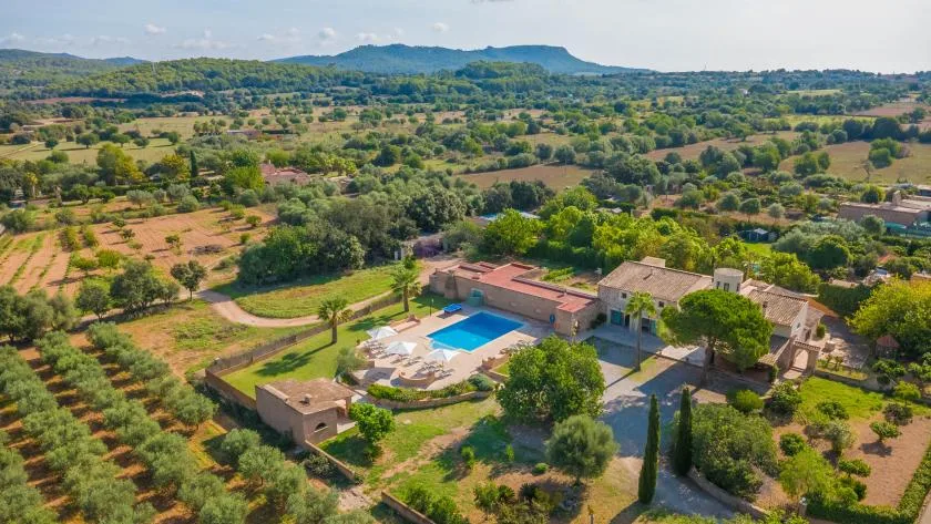 Una propiedad rural con piscina está rodeada de campos y colinas onduladas.