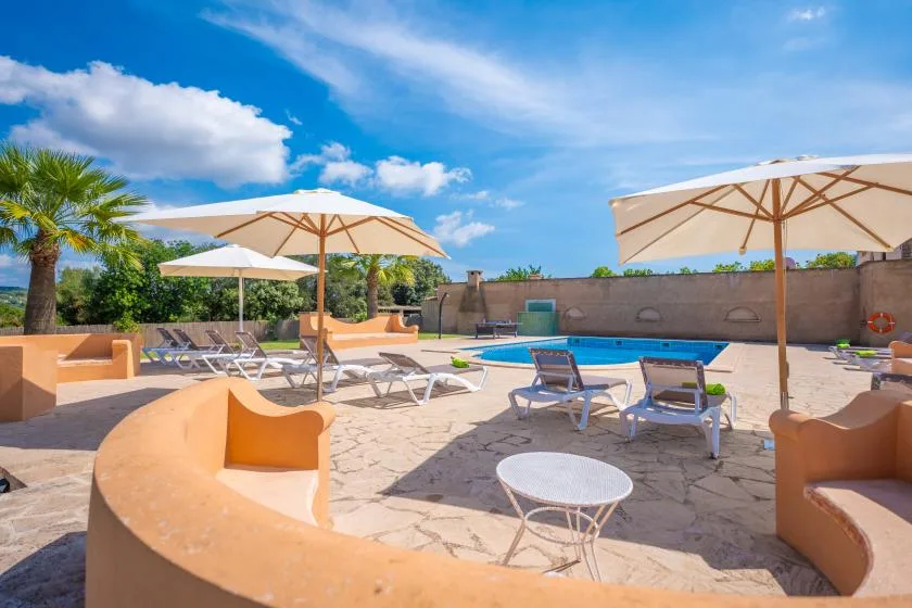 Una piscina al aire libre está rodeada de asientos y grandes sombrillas.