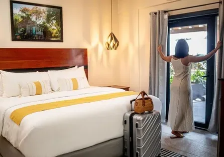 Guest standing in a hotel room with a suitcase.