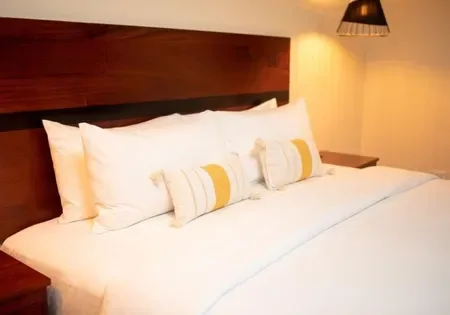 Cama con sábanas blancas y almohadas amarillas.