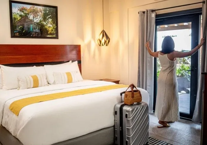 Guest standing in a hotel room with a suitcase.