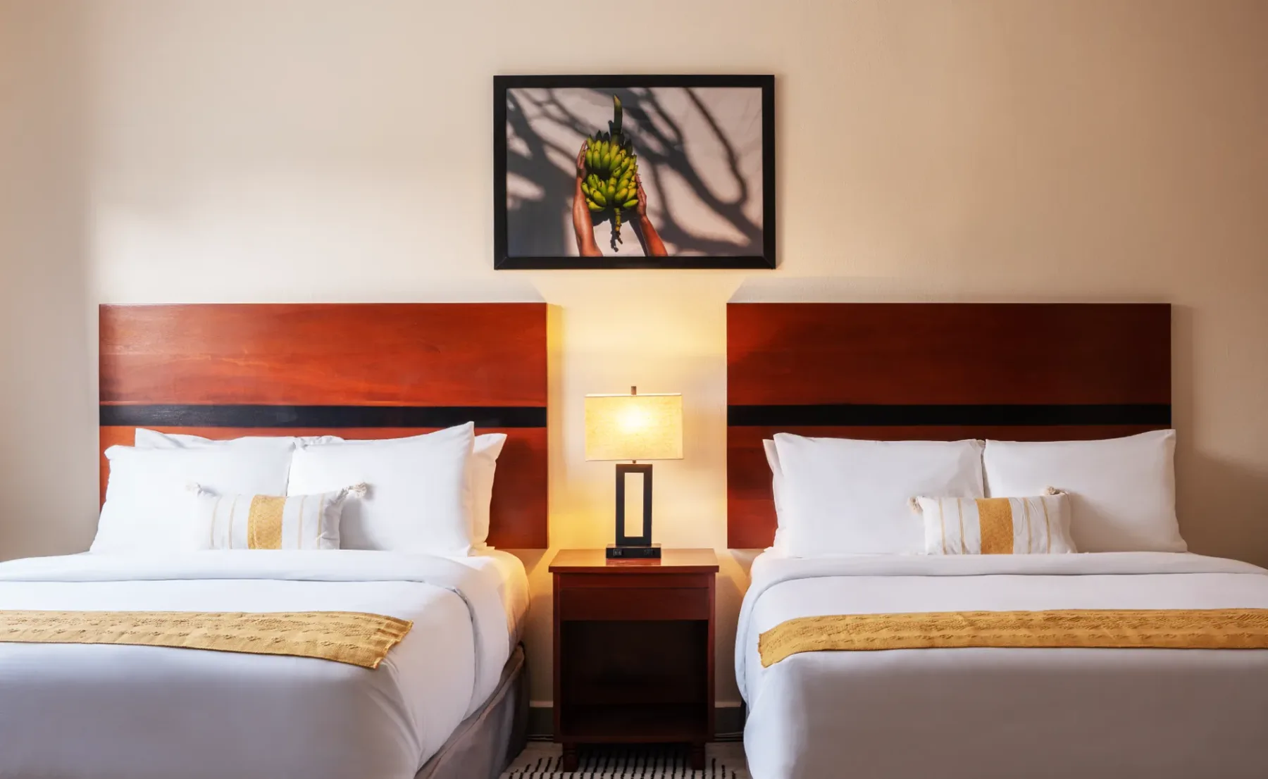 Hotel room with two beds, a nightstand and a lamp.
