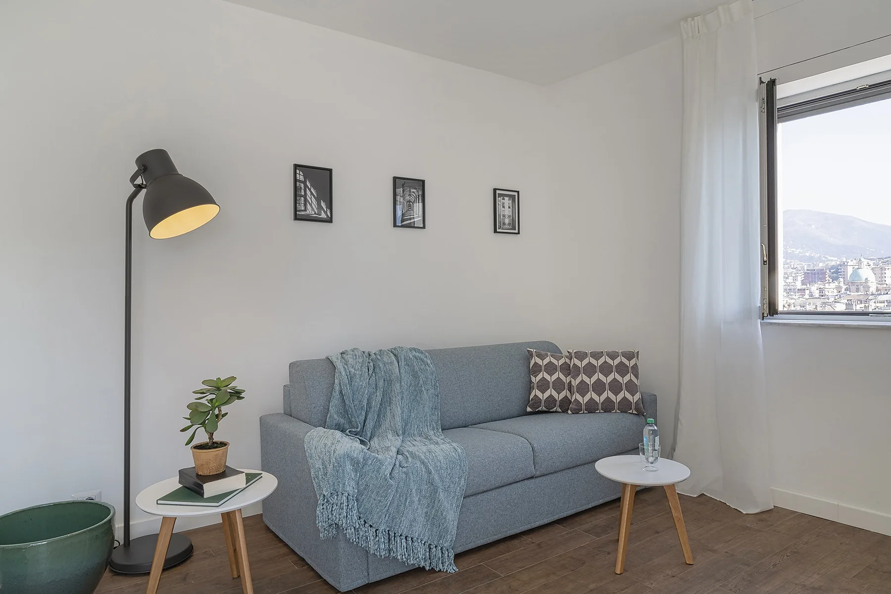 A bright living room with a gray sofa, floor lamp, and large window.
