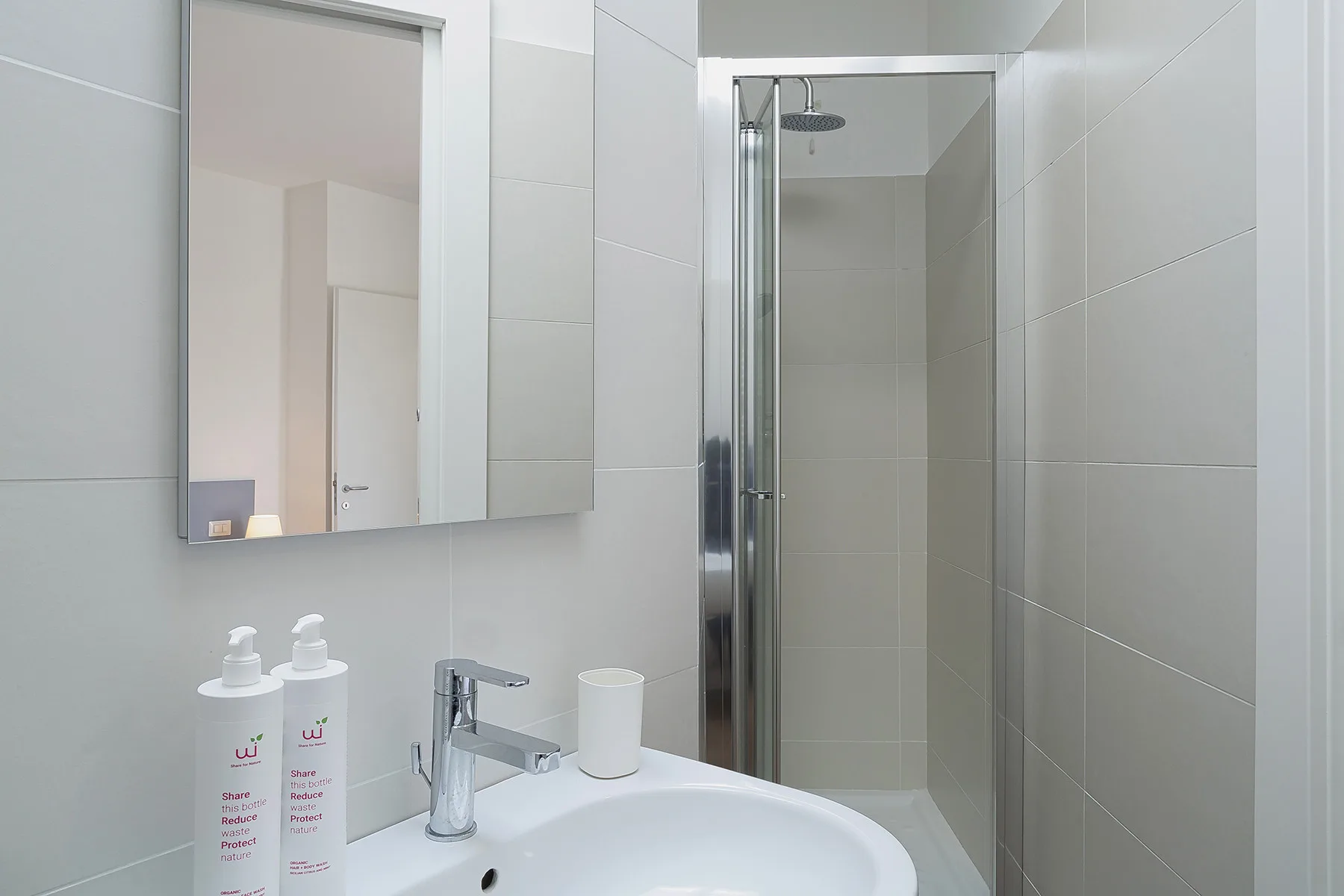 A tiled bathroom with a sink, wall mirror, and glass shower.