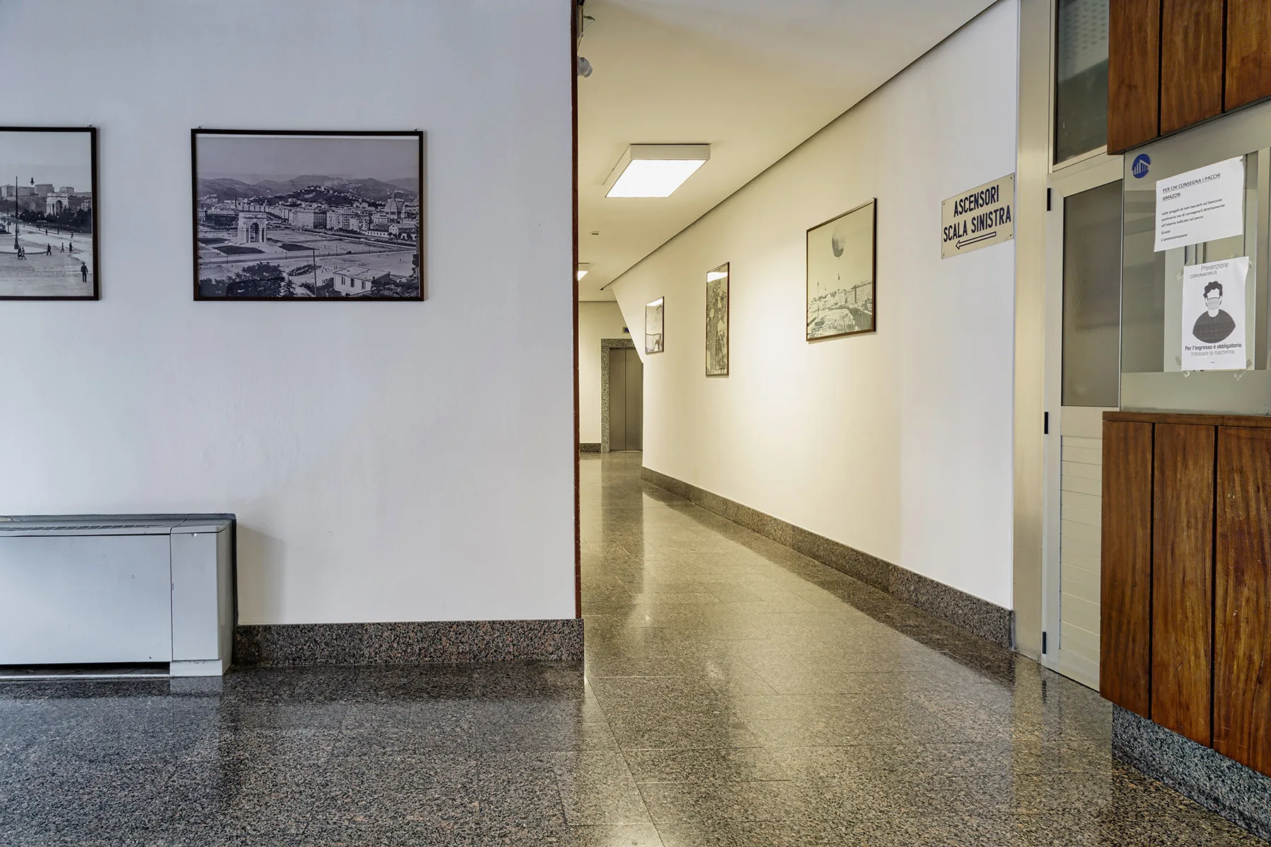 A hallway with framed pictures and a polished floor.