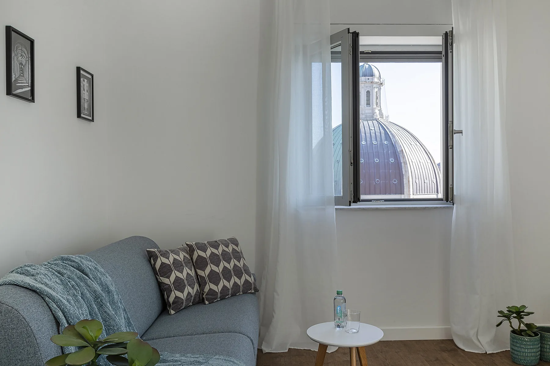 A sitting area with blue seating beside a window overlooking a domed roof.