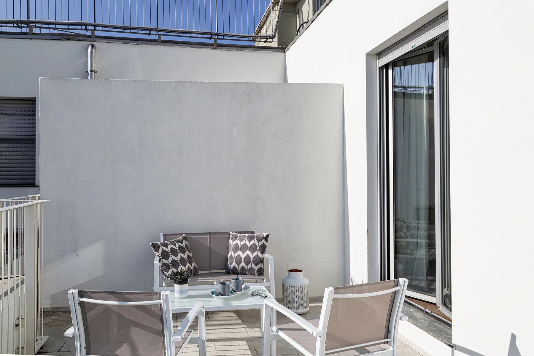 A small outdoor terrace with seating and a glass-topped table.