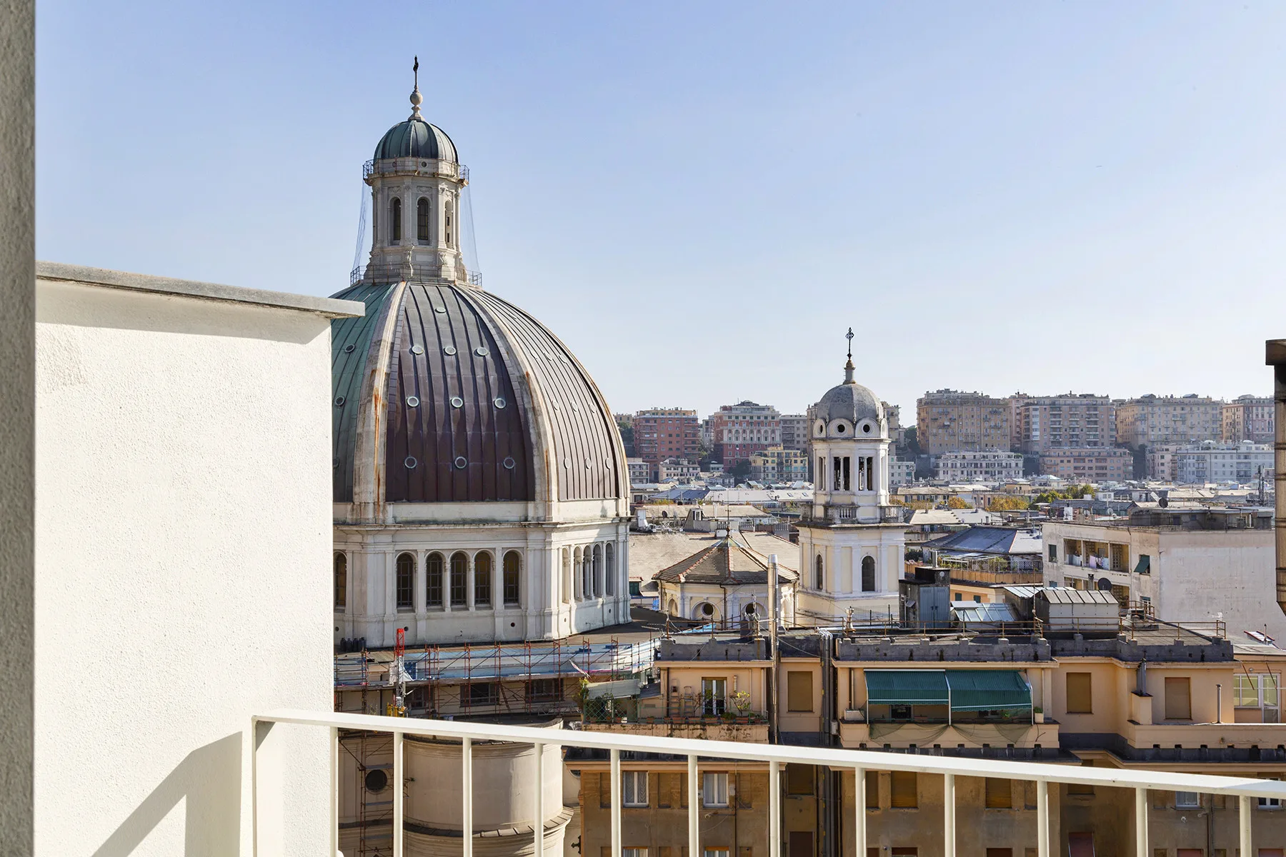 A rooftop terrace overlooks a city skyline and a prominent domed building.