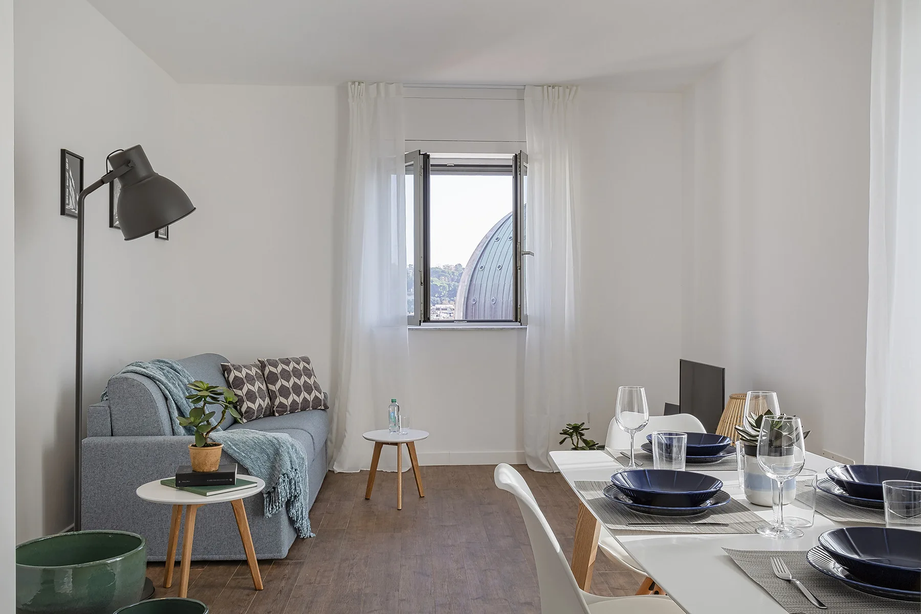 A bright living and dining area with seating beside a set table.