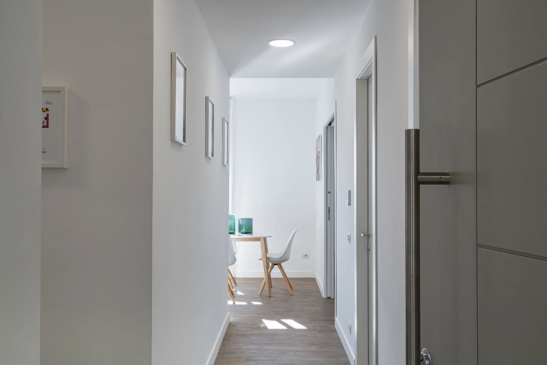 A bright hallway with framed pictures and a small seating area at the far end.