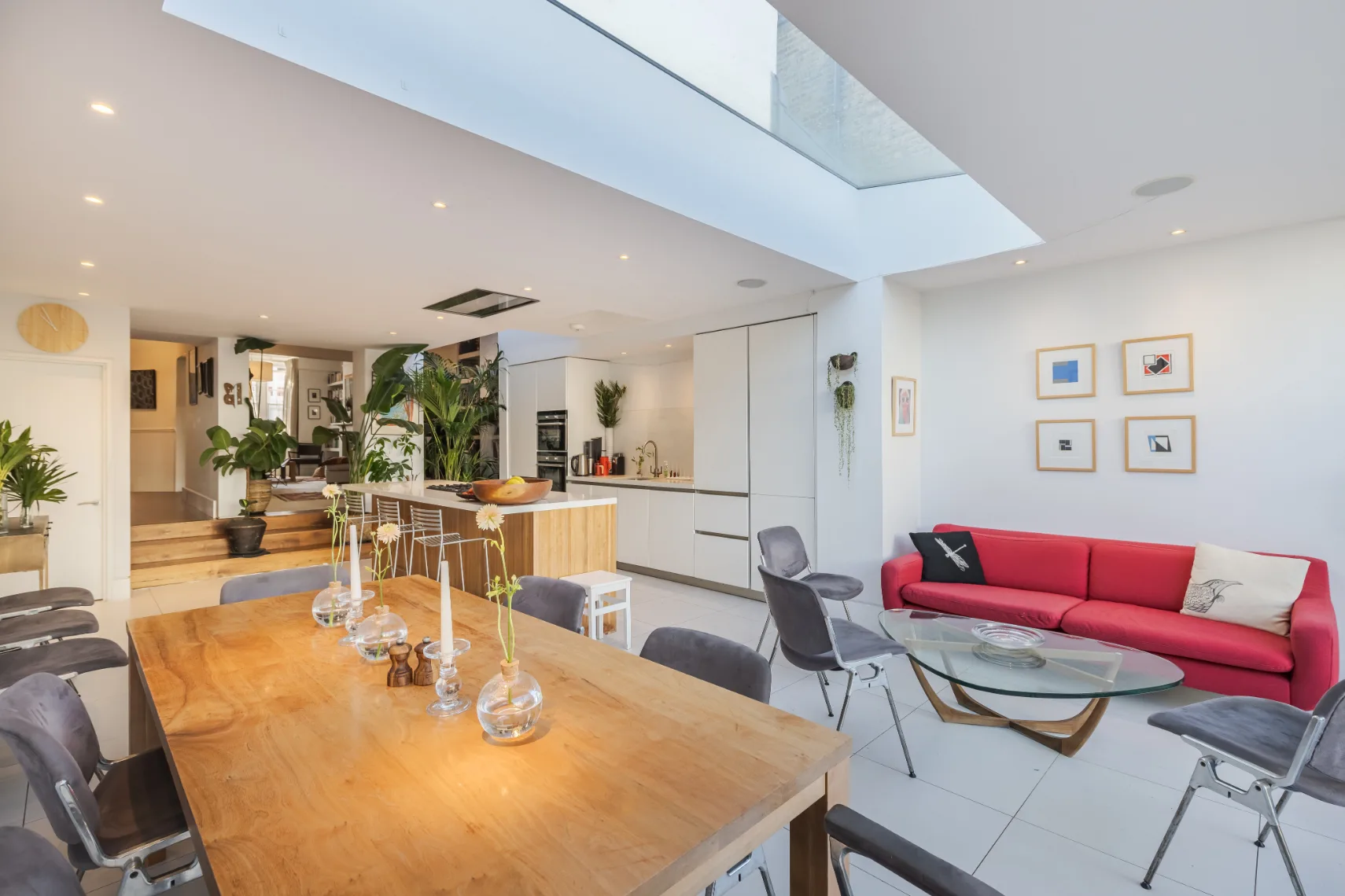 Open-plan living and dining area with a red sofa and wooden dining table.