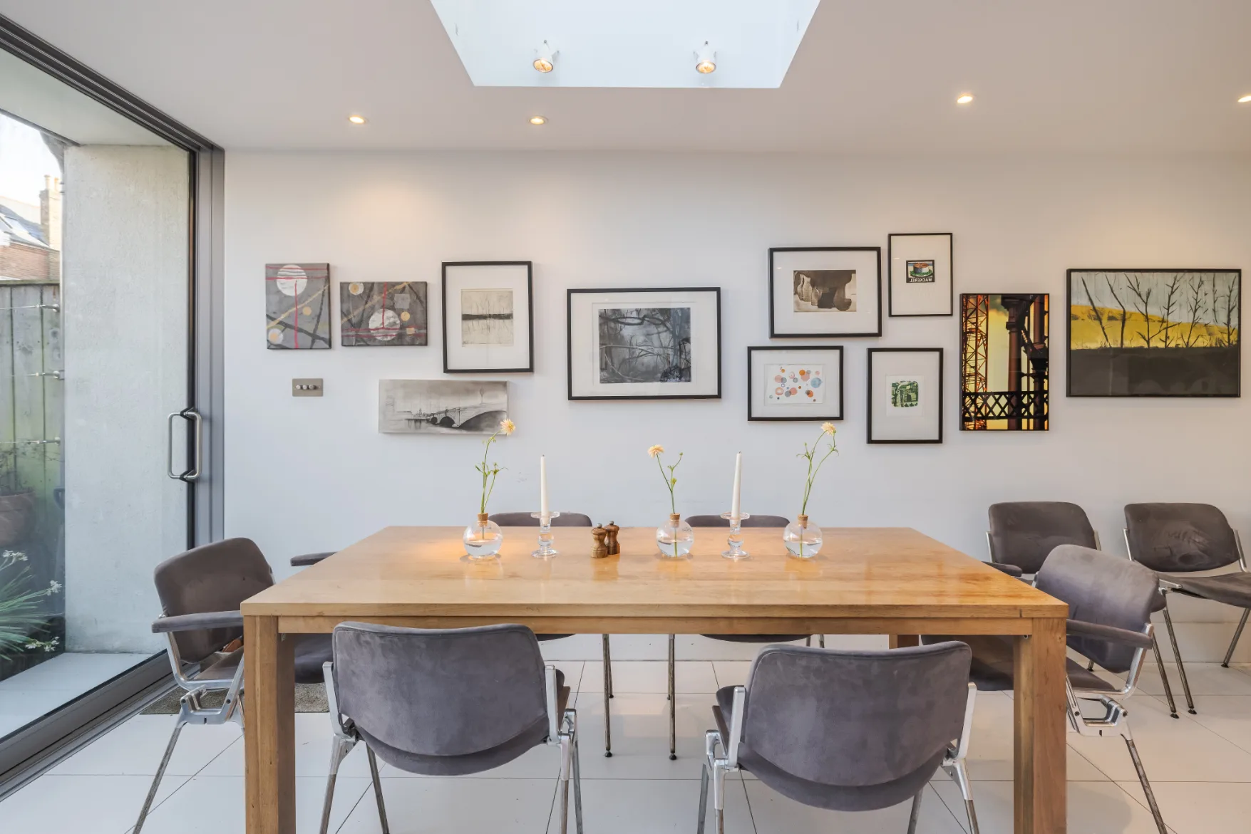 Un comedor con una mesa de madera, asientos y cuadros enmarcados en la pared.