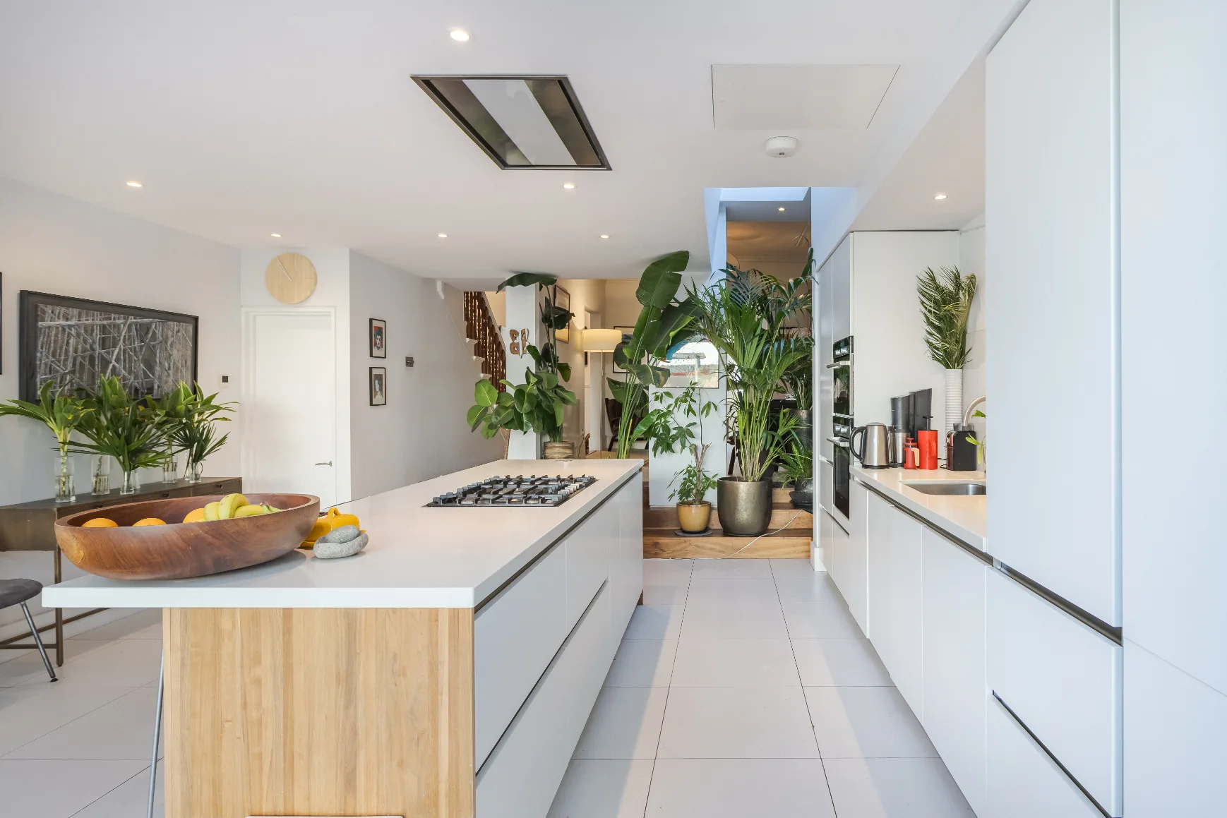 Una cocina moderna y luminosa con una isla larga y plantas.