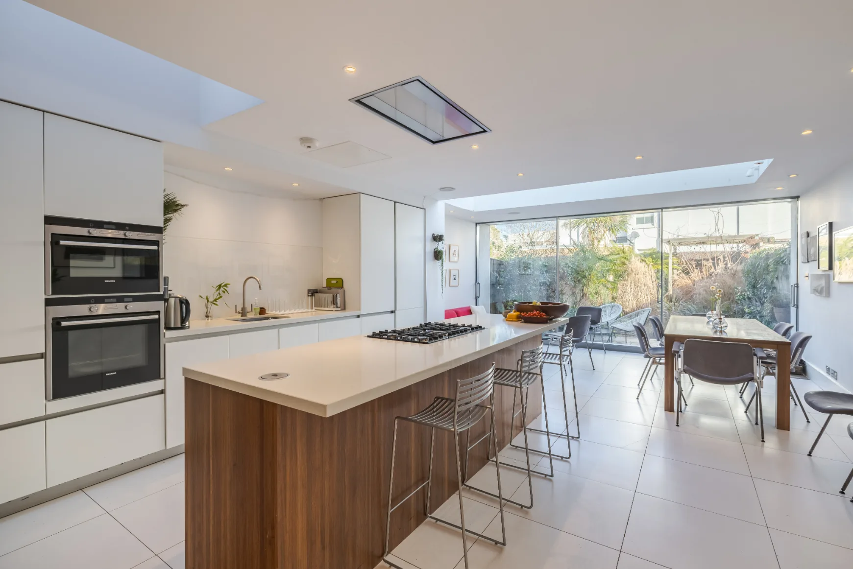 A bright modern kitchen with an island and dining area beside large windows.