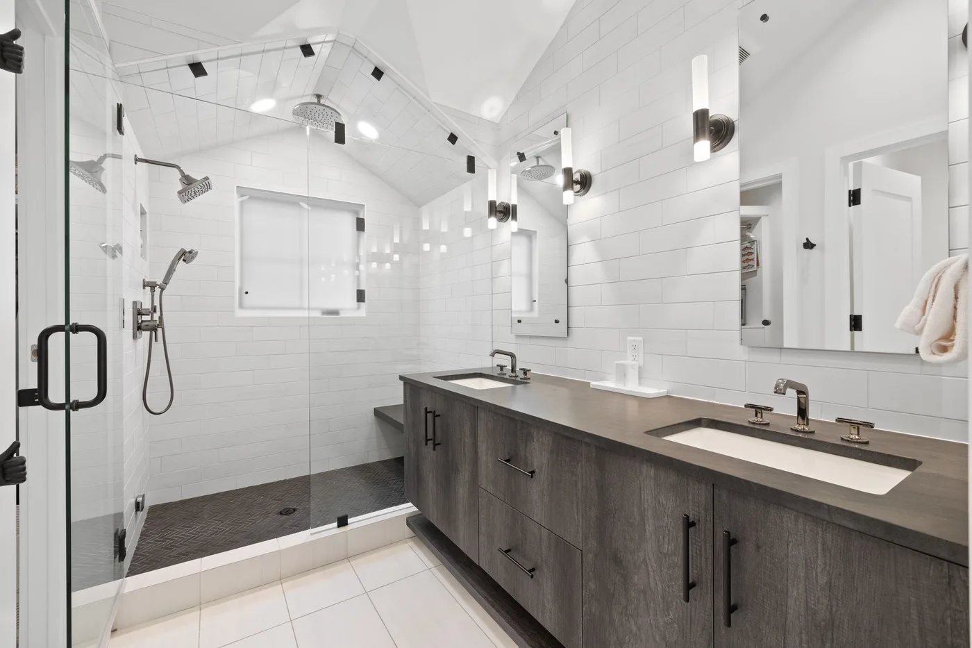 Un baño luminoso con un tocador largo y una ducha con mampara de vidrio.