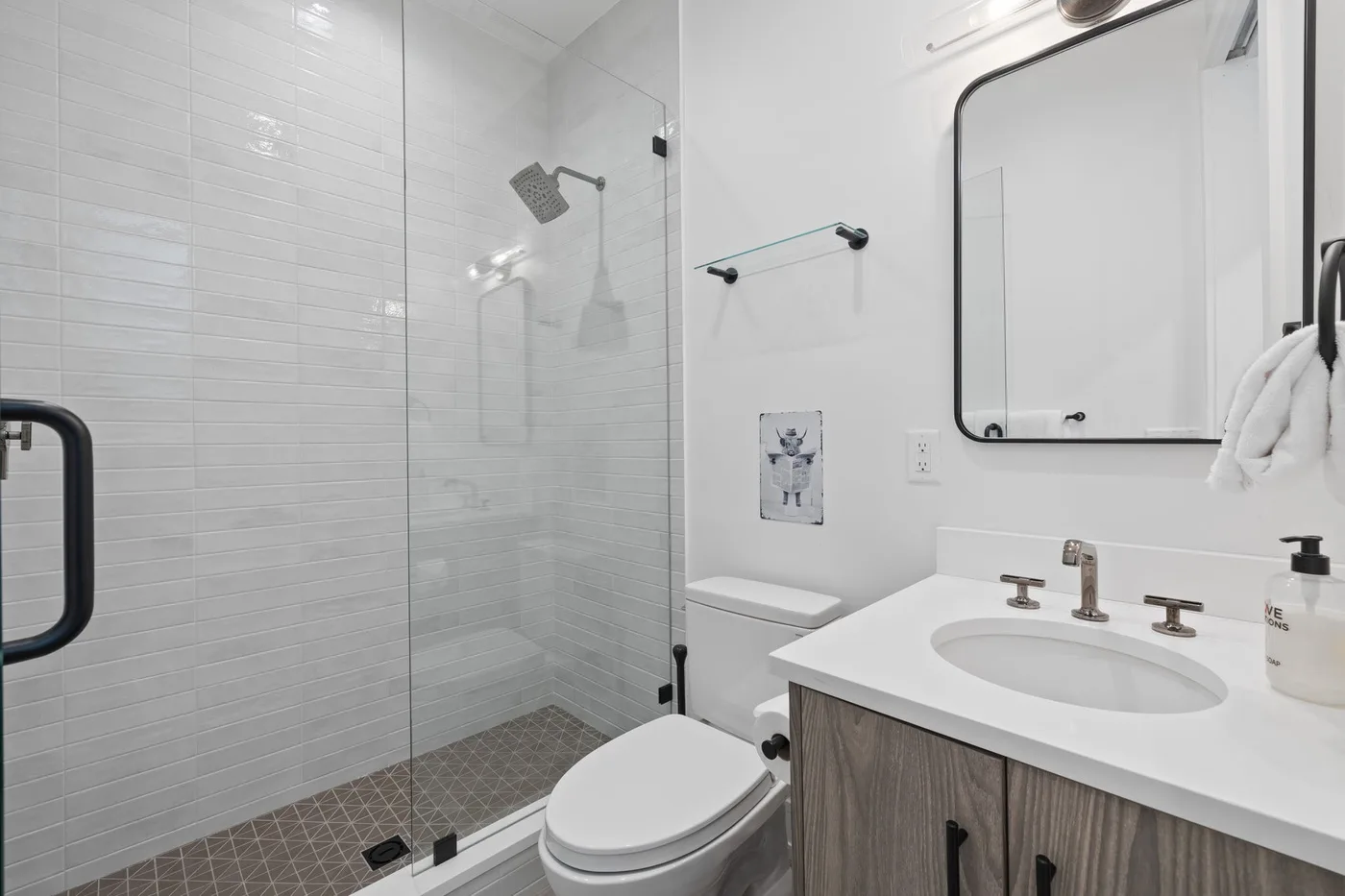 Un baño luminoso con ducha de vidrio, inodoro y lavabo.