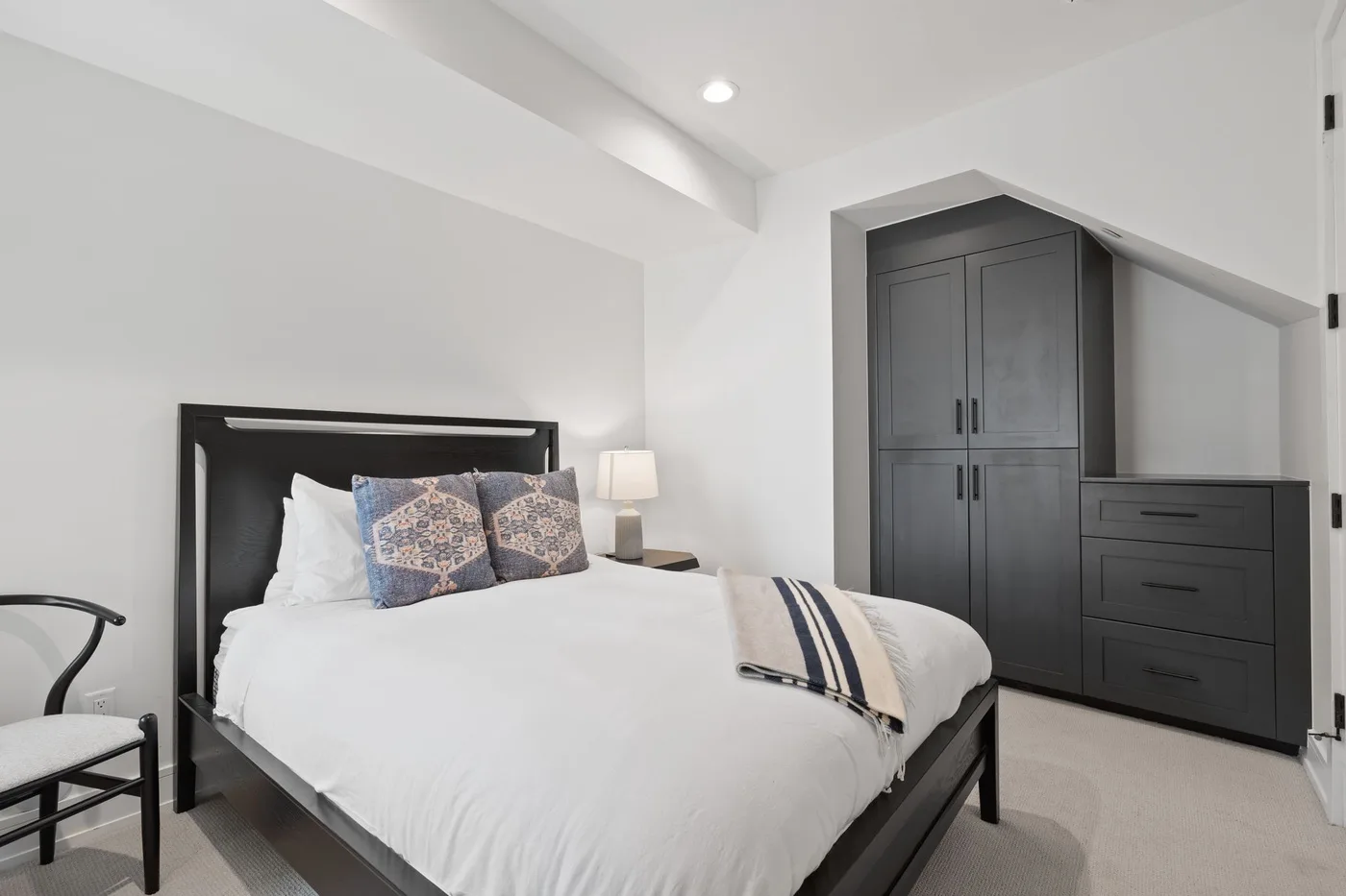 Un dormitorio luminoso con una cama y armarios oscuros empotrados.