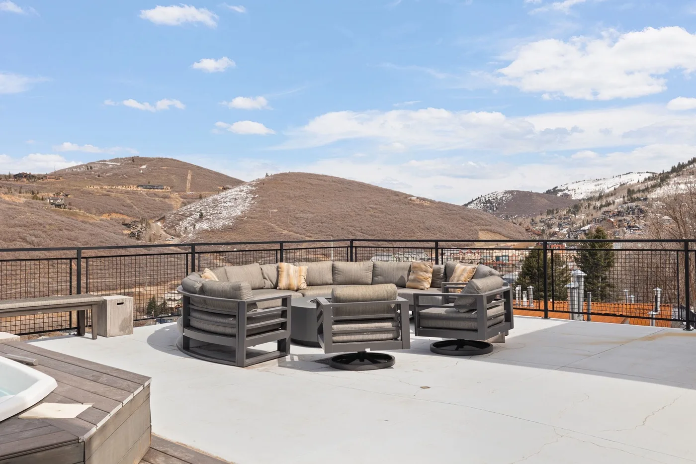 Una terraza en la azotea con asientos al aire libre mira hacia colinas bajo un cielo azul.