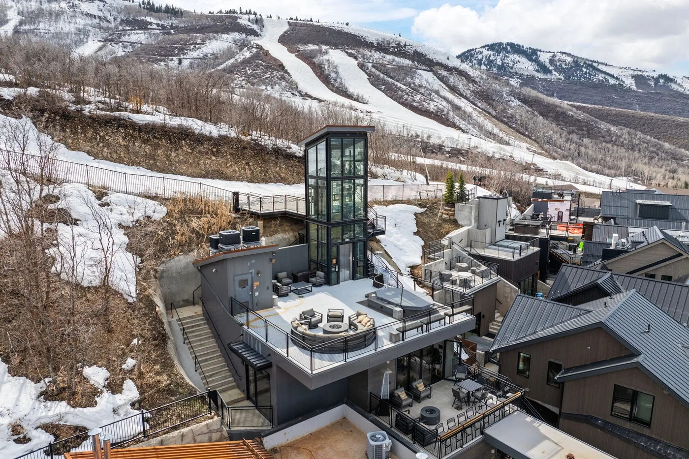 Un complejo turístico moderno de montaña se encuentra bajo pistas de esquí nevadas.