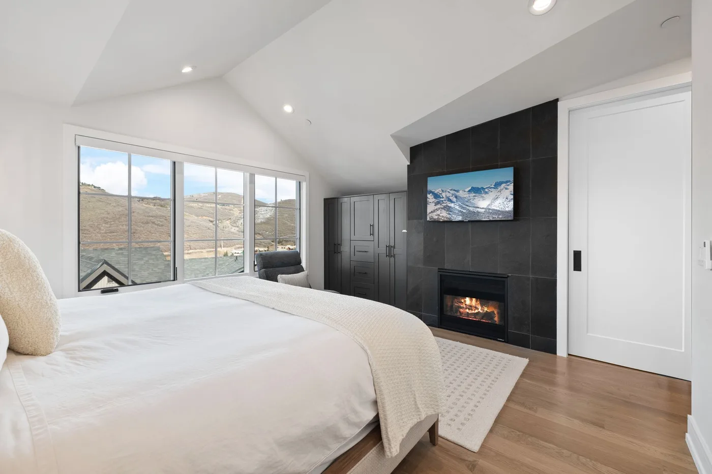 Un dormitorio luminoso con una cama grande, amplias ventanas y una chimenea.