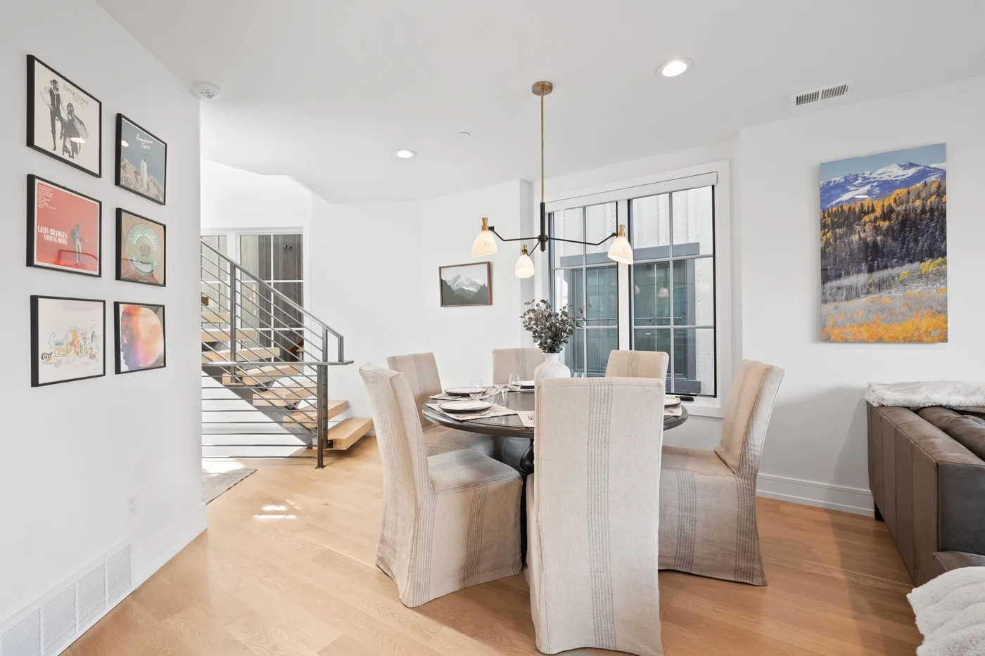 Un comedor luminoso con una mesa y sillas junto a una escalera.