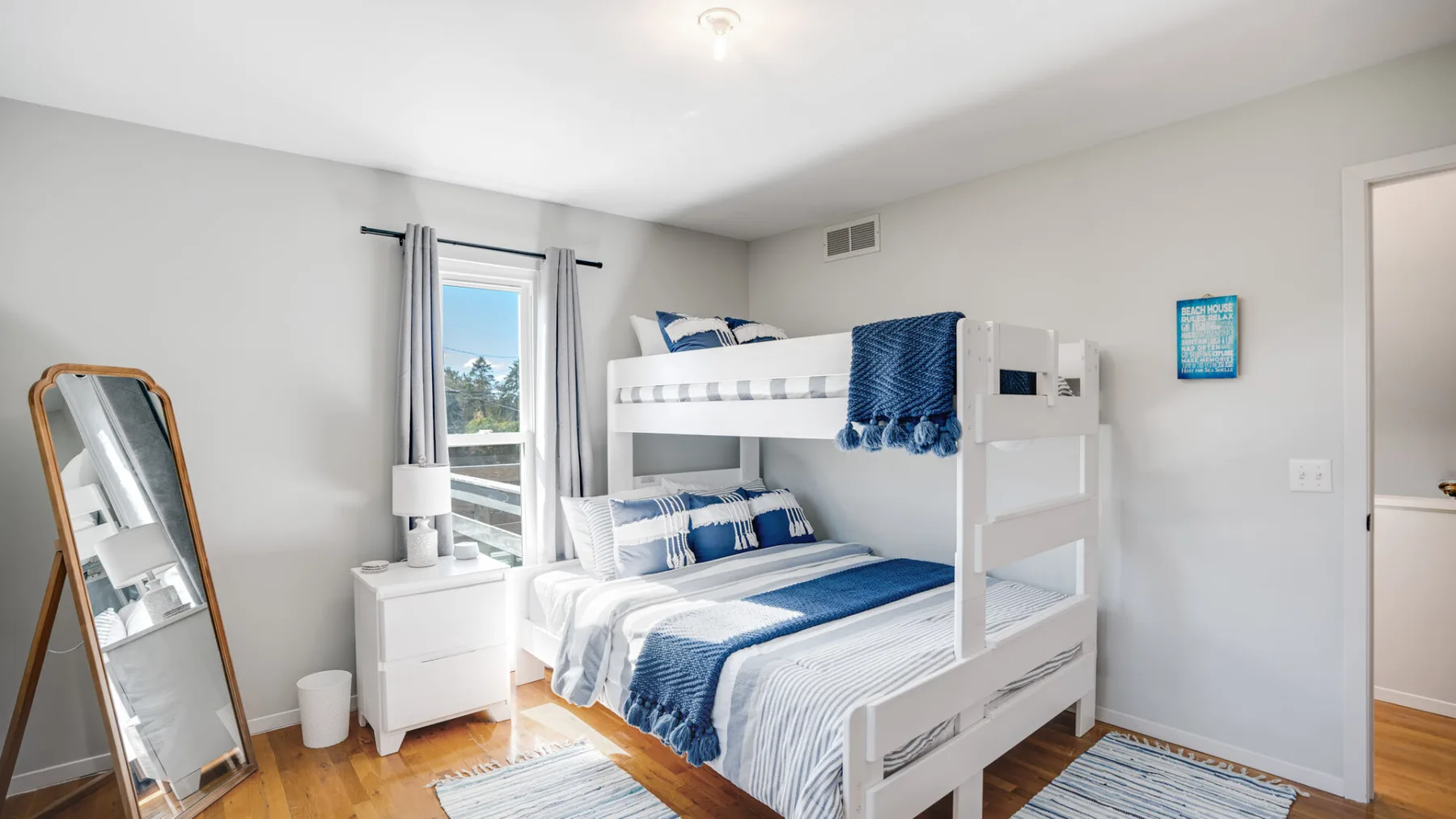 A bright bedroom with white bunk beds and blue bedding.